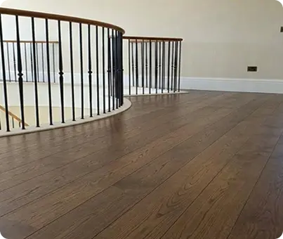 Dark-oak-hardwood-floors-on-an-upper-landing-with-curved-iron-staircase-railing