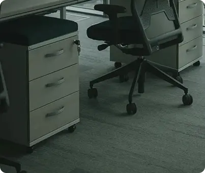 Close-up-of-light-wood-flooring-under-an-office-desk-and-ergonomic-chair.png
