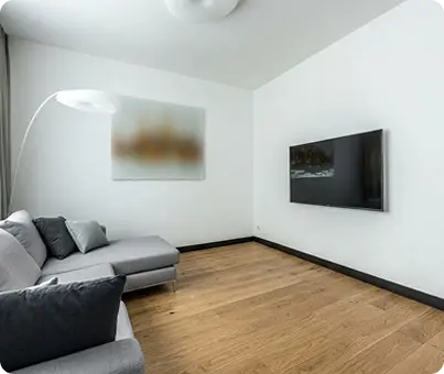 Minimalist-living-room-with-oak-hardwood-floors-gray-sectional-and-wall-mounted-TV