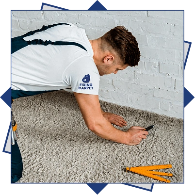 Carpet installer measuring and cutting wall to wall carpet along a white brick wall during wall to wall carpet installation
