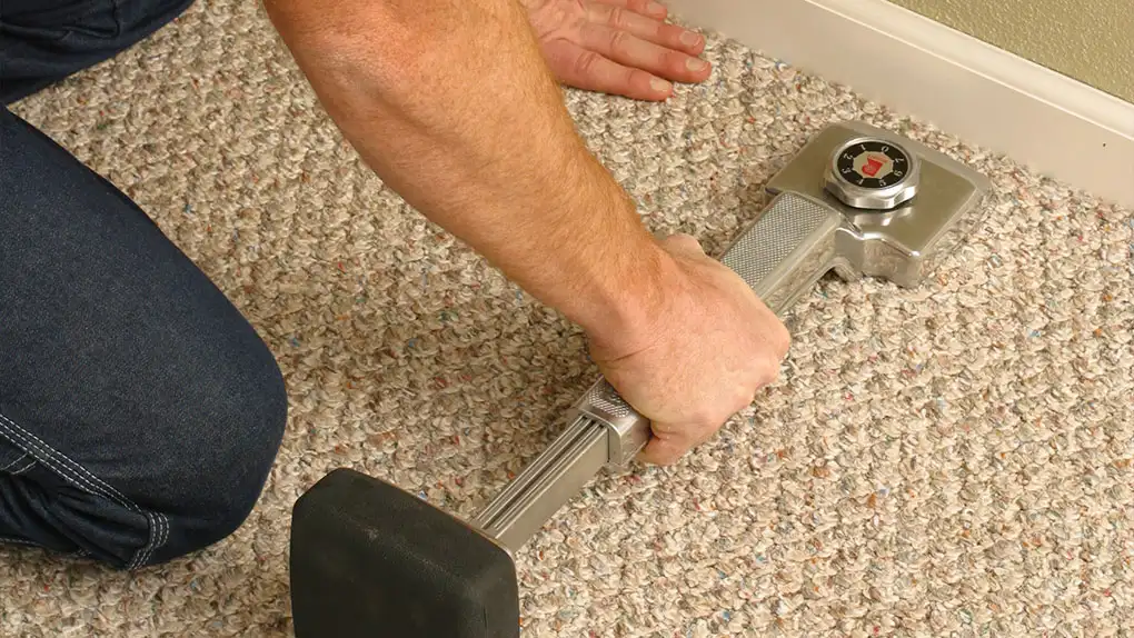 Person using a carpet stretcher tool on a jute carpet during jute carpet installation