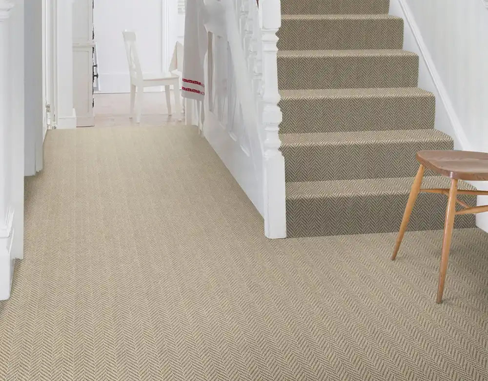 Bright hallway and staircase featuring beige herringbone patterned carpet flooring
