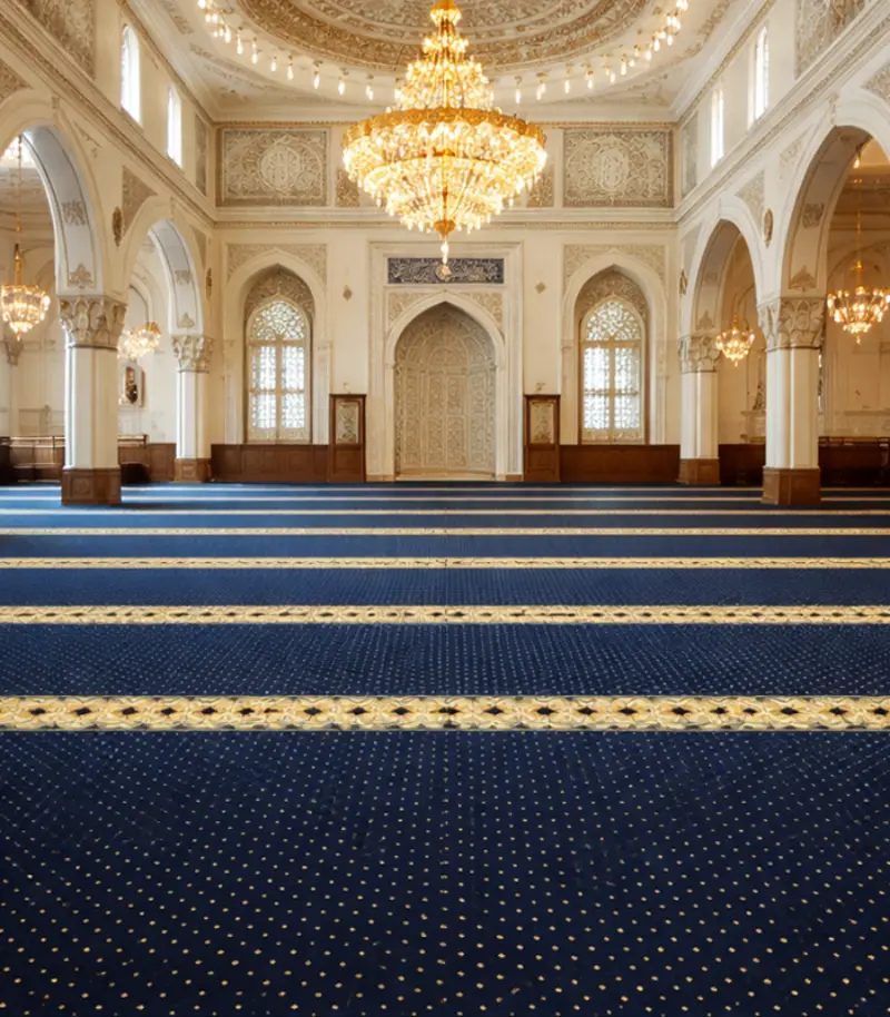 Grand mosque interior featuring blue and gold prayer carpet under a large crystal chandelier