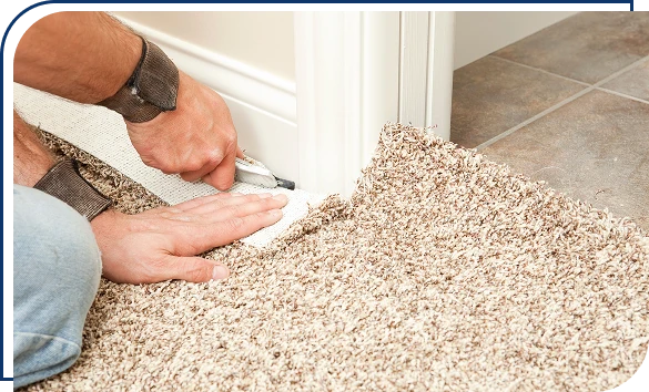 Installer using a utility knife to trim beige plush carpet along a doorway during installation
