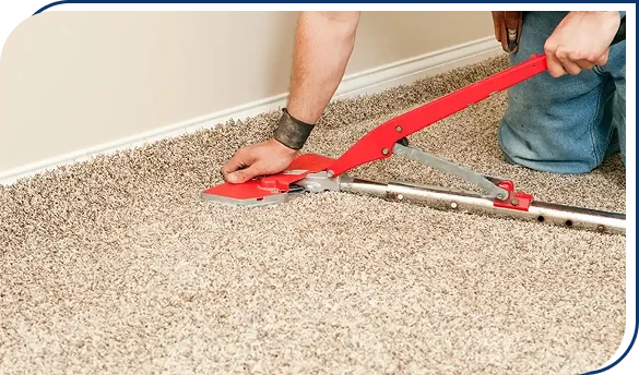 Professional installer using a power stretcher tool to stretch beige plush carpet during installation